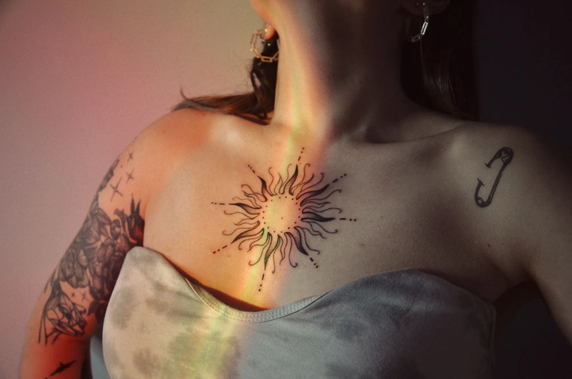 Soare ornamental cu raze fine, tatuat sub claviculă